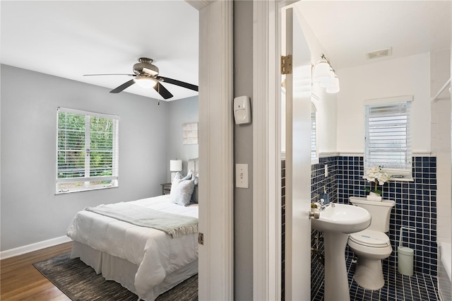 bedroom with tile walls, sink, and dark hardwood / wood-style floors