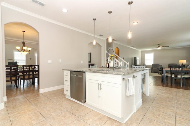 kitchen featuring white cabinetry, light stone countertops, an island with sink, decorative light fixtures, and stainless steel dishwasher