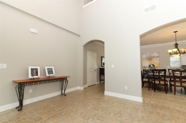 interior space featuring tile patterned flooring, ornamental molding, a high ceiling, and an inviting chandelier