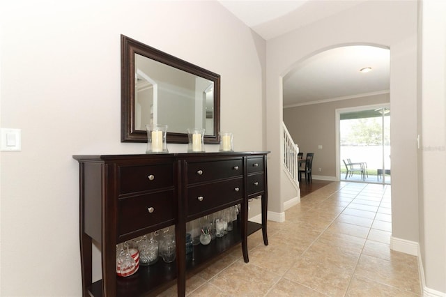 hallway with ornamental molding and light tile patterned floors