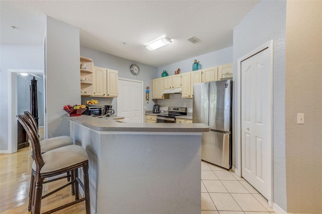 kitchen with a kitchen bar, sink, light tile patterned floors, stainless steel appliances, and kitchen peninsula