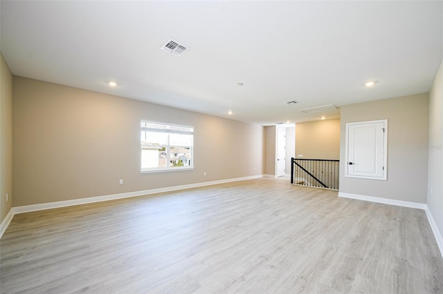 empty room with light wood-style floors, recessed lighting, visible vents, and baseboards