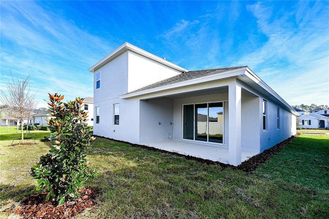 view of side of property with a yard, a patio, and stucco siding