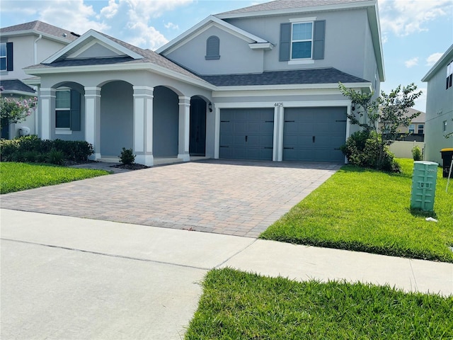 4425 Lions Gate Ave, Clermont, FL 34711 - view of front facade featuring stucco siding, decorative driveway, a front yard, roof with shingles, and an attached garage