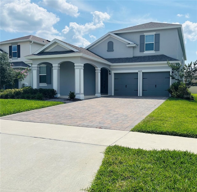 4425 Lions Gate Ave, Clermont, FL 34711 - view of front of property featuring decorative driveway, stucco siding, a front lawn, a porch, and an attached garage
