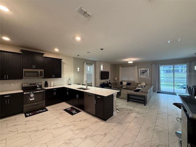 kitchen with tasteful backsplash, sink, stainless steel appliances, and kitchen peninsula