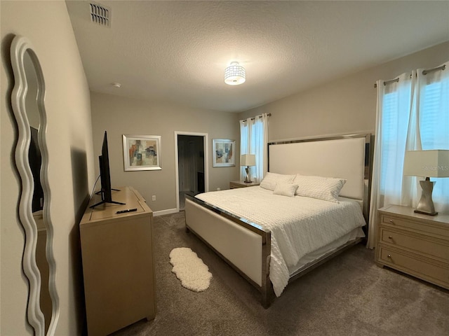 bedroom with multiple windows, dark colored carpet, and a textured ceiling