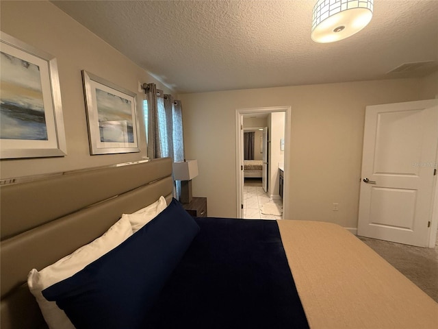 bedroom featuring ensuite bathroom and a textured ceiling