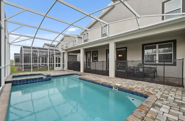 view of swimming pool featuring an in ground hot tub, glass enclosure, and a patio