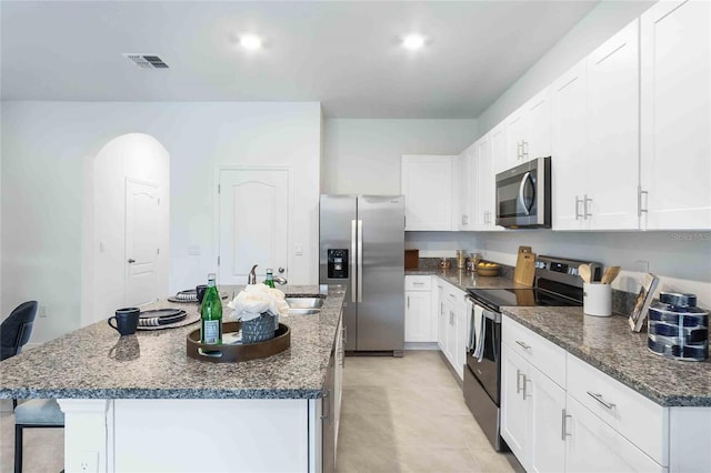 kitchen with stainless steel appliances, a center island with sink, and white cabinets