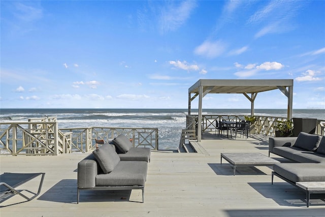 wooden deck featuring an outdoor living space, a water view, and a beach view