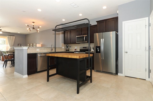 kitchen with stainless steel appliances, a center island, dark brown cabinetry, wood counters, and decorative backsplash