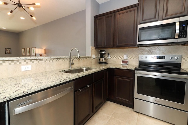 kitchen featuring appliances with stainless steel finishes, light stone countertops, sink, and decorative backsplash