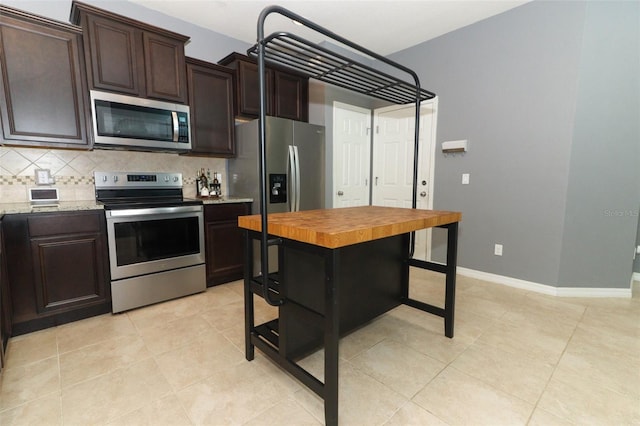 kitchen with dark brown cabinetry, butcher block countertops, and appliances with stainless steel finishes