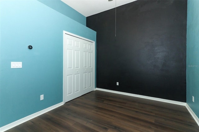 unfurnished bedroom with dark wood-type flooring and a closet