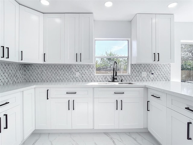 kitchen with light stone countertops, sink, white cabinetry, and tasteful backsplash