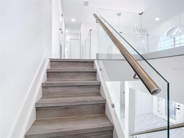 staircase with hardwood / wood-style flooring and a notable chandelier