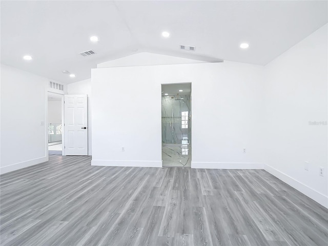 empty room with vaulted ceiling, a wealth of natural light, and hardwood / wood-style floors