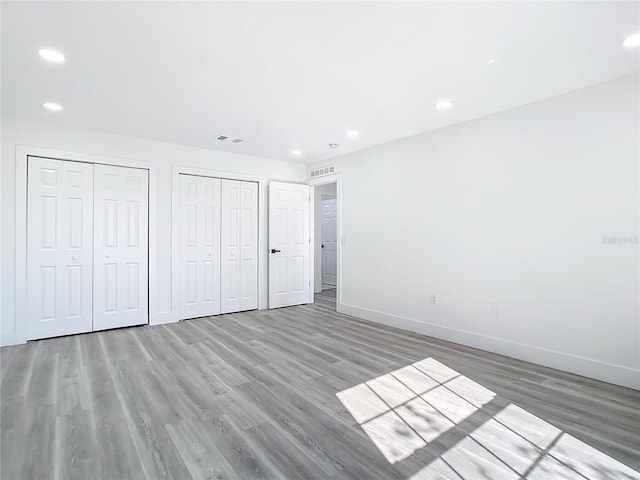 unfurnished bedroom featuring hardwood / wood-style flooring and two closets