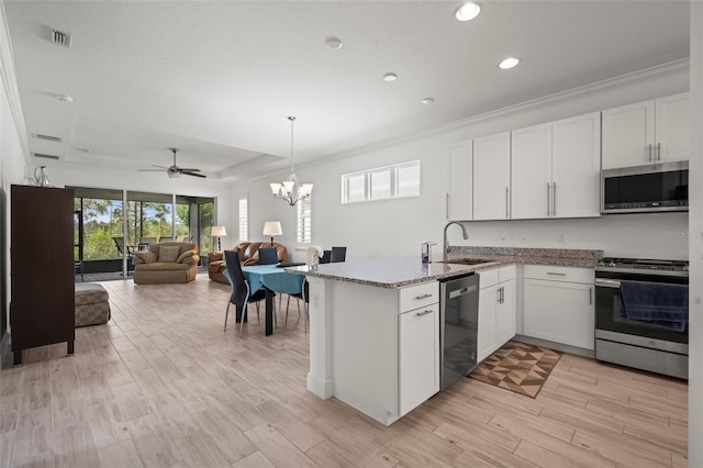 kitchen featuring sink, stainless steel appliances, light hardwood / wood-style floors, white cabinets, and decorative light fixtures