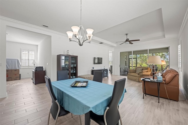 dining space featuring ornamental molding, a raised ceiling, and light wood-type flooring