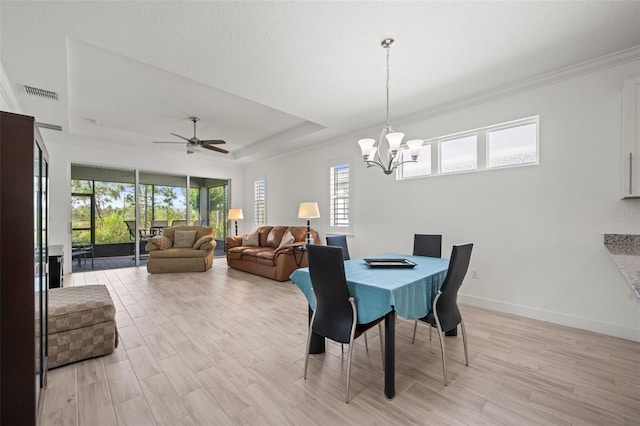 dining space with crown molding, a raised ceiling, ceiling fan with notable chandelier, and light wood-type flooring