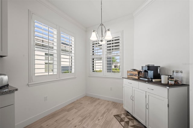 dining space featuring ornamental molding, a chandelier, and light hardwood / wood-style floors