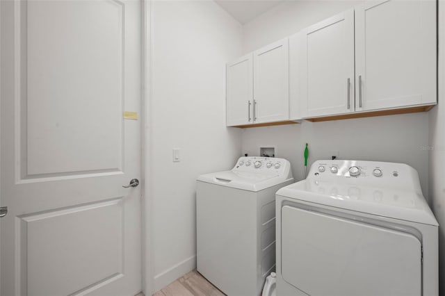 laundry area featuring independent washer and dryer, light hardwood / wood-style flooring, and cabinets