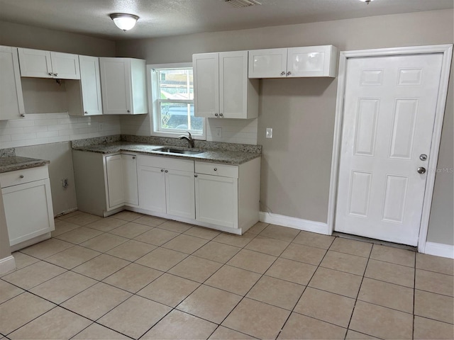 kitchen with tasteful backsplash, sink, a textured ceiling, and white cabinets