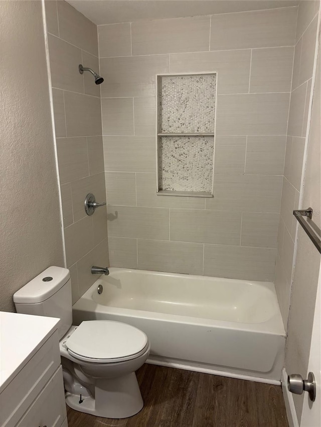 full bathroom with vanity, tiled shower / bath, hardwood / wood-style flooring, and toilet