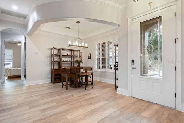 entrance foyer with crown molding, ceiling fan with notable chandelier, a raised ceiling, and light hardwood / wood-style floors