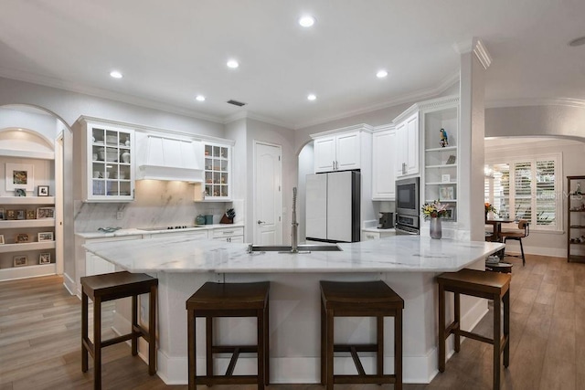 kitchen with white cabinetry, stainless steel appliances, a breakfast bar area, and custom exhaust hood