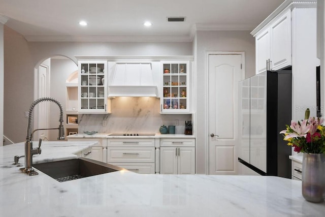 kitchen featuring sink, custom exhaust hood, white cabinetry, refrigerator, and black electric stovetop