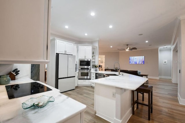 kitchen featuring sink, a breakfast bar, stainless steel appliances, white cabinets, and kitchen peninsula