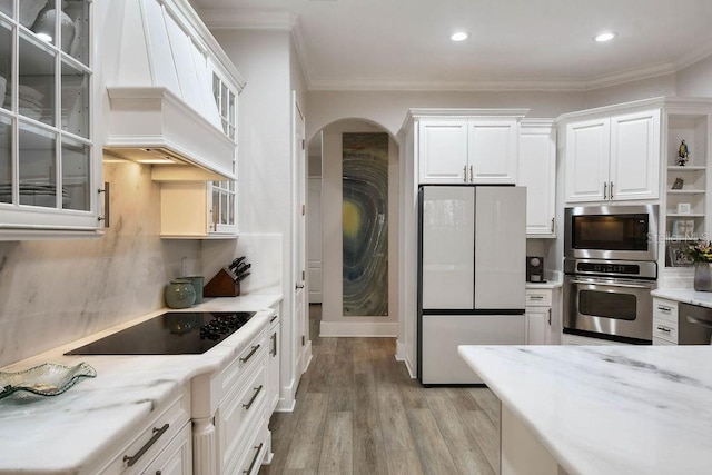 kitchen featuring white refrigerator, custom range hood, black electric stovetop, oven, and white cabinets