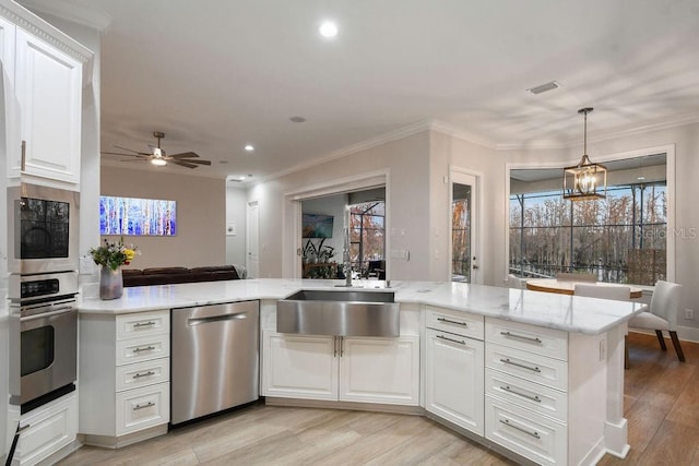 kitchen featuring white cabinetry, sink, kitchen peninsula, stainless steel appliances, and crown molding