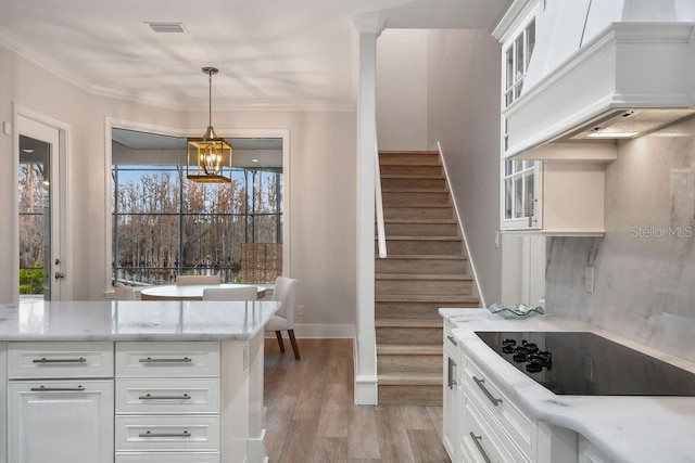 kitchen with pendant lighting, white cabinetry, black electric stovetop, light hardwood / wood-style floors, and custom exhaust hood