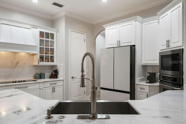 kitchen featuring fridge, light stone countertops, white cabinets, built in microwave, and oven