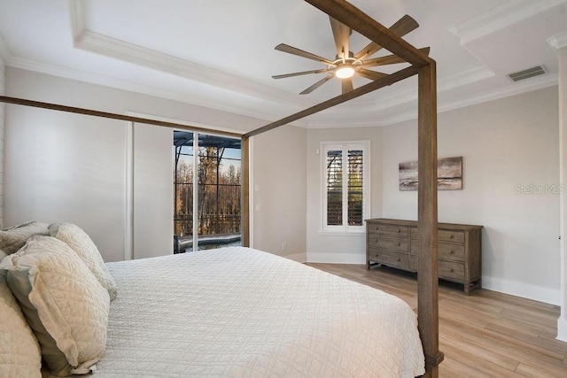 bedroom featuring light wood-type flooring, ornamental molding, a raised ceiling, ceiling fan, and access to exterior