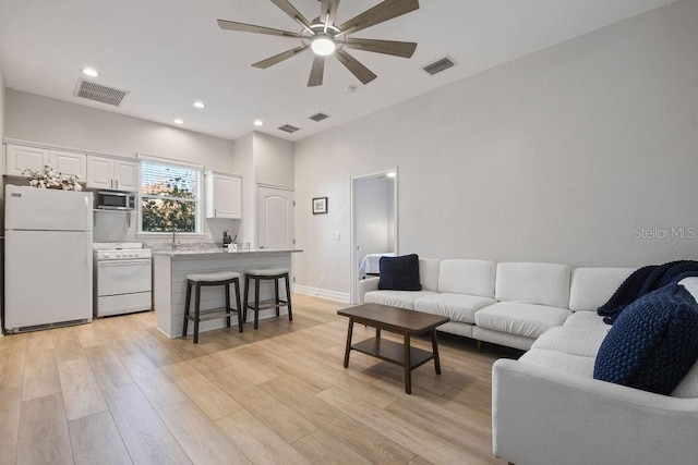 living room with sink, light hardwood / wood-style flooring, and ceiling fan