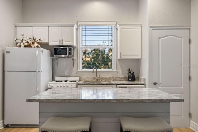 kitchen with a breakfast bar area, sink, white fridge, and white cabinets