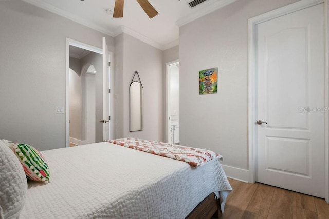 bedroom featuring crown molding, ceiling fan, wood-type flooring, and ensuite bathroom