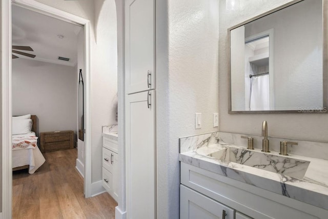 bathroom with ceiling fan, vanity, wood-type flooring, and ornamental molding