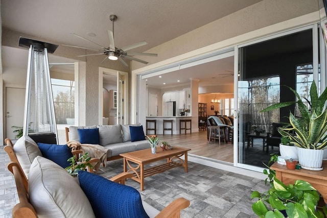 sunroom / solarium featuring ceiling fan with notable chandelier