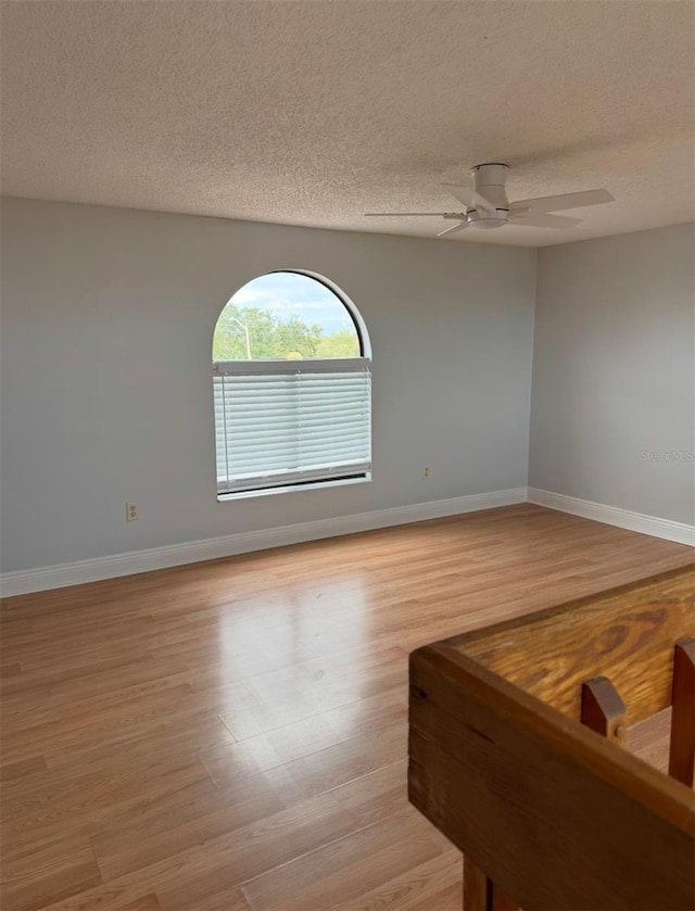 spare room with ceiling fan, light hardwood / wood-style flooring, and a textured ceiling