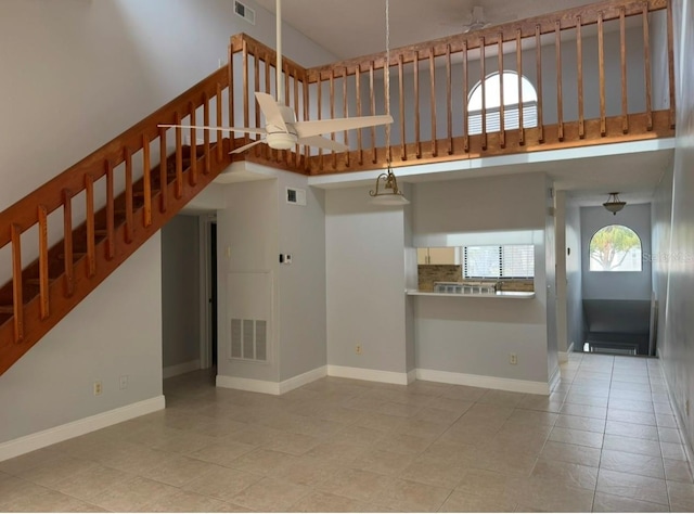 unfurnished living room featuring light tile patterned flooring, a healthy amount of sunlight, and a high ceiling