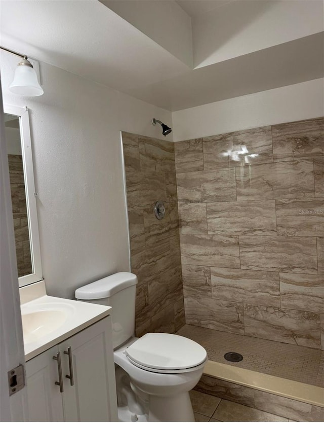 bathroom featuring tiled shower, vanity, toilet, and tile patterned floors