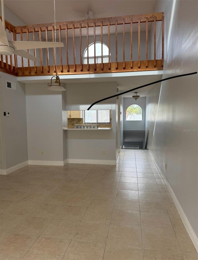 unfurnished living room with light tile patterned floors and a high ceiling