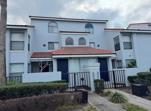 4826 Marks Ter Unit 389, Orlando, FL 32811 - view of front facade featuring a tiled roof, a fenced front yard, and stucco siding