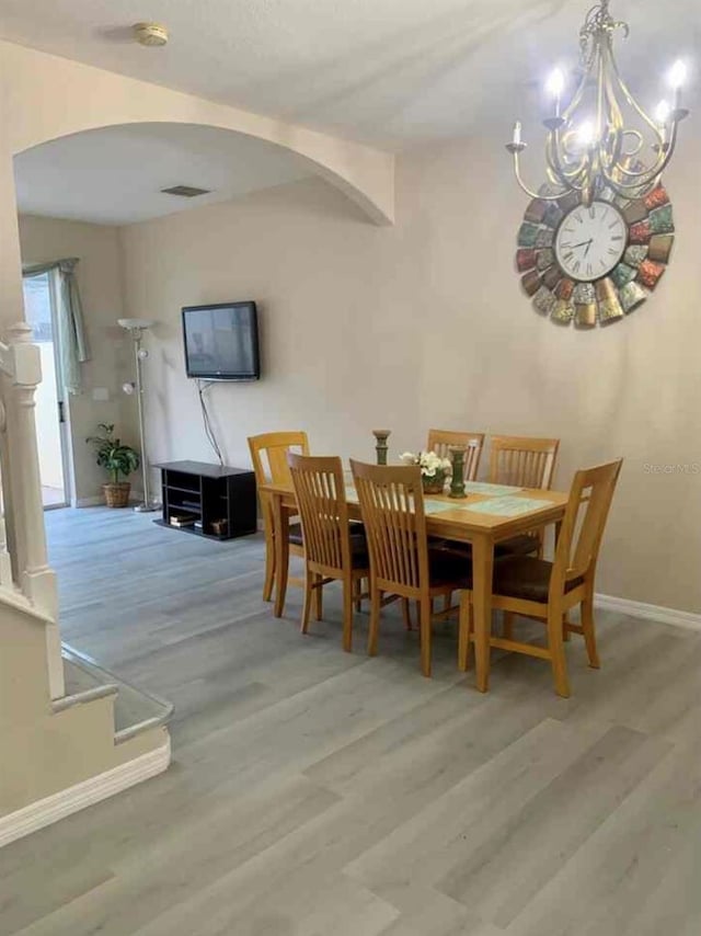 dining space featuring light hardwood / wood-style flooring and a notable chandelier